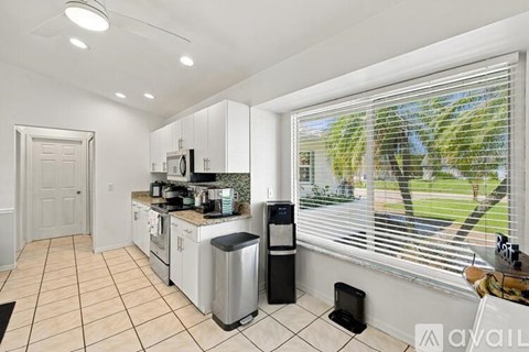 A kitchen with white cabinets and a black trash can.