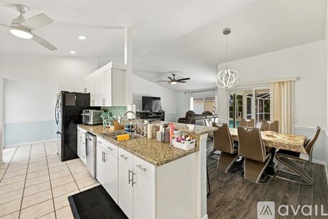 A kitchen with a black refrigerator and a granite countertop.