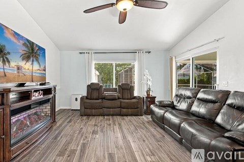 A living room with a brown leather couch and a wall mural of a beach scene.