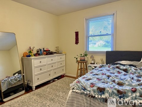 A bedroom with a bed, dresser, and window.