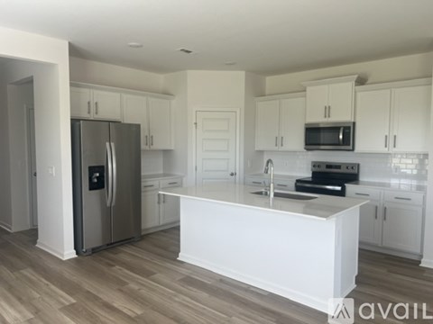 A kitchen with white cabinets and a stainless steel refrigerator.