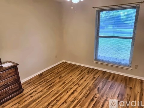 A room with wooden flooring and a window showing a view of a pool.