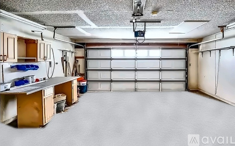 A spacious garage with a ceiling fan and a workbench.