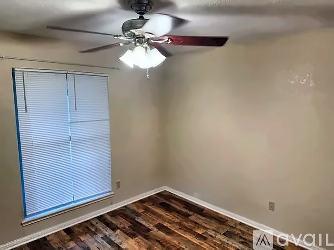 A room with a ceiling fan and a window with blinds.