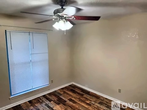 A room with a ceiling fan and a window with blinds.