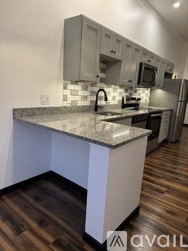 A kitchen with a granite countertop and wooden flooring.
