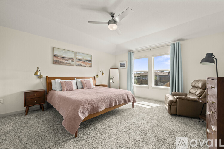 A bedroom with a bed, chair, and fan.