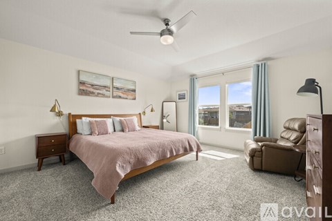 A bedroom with a bed, chair, and fan.