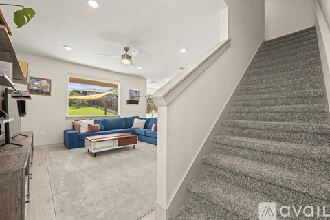 A living room with a blue couch and a staircase.