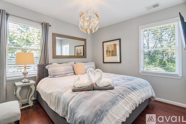 A bedroom with a bed, a chandelier, and a window with a view of trees.