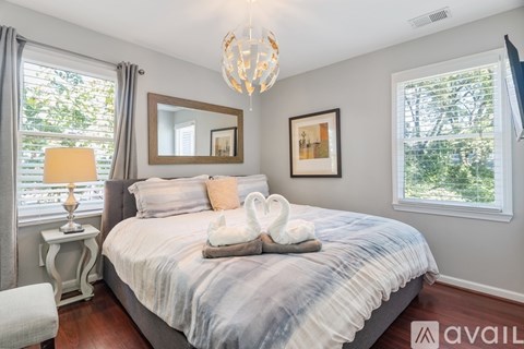 A bedroom with a bed, a chandelier, and a window with a view of trees.