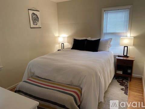 A bedroom with a white bed and striped blanket.