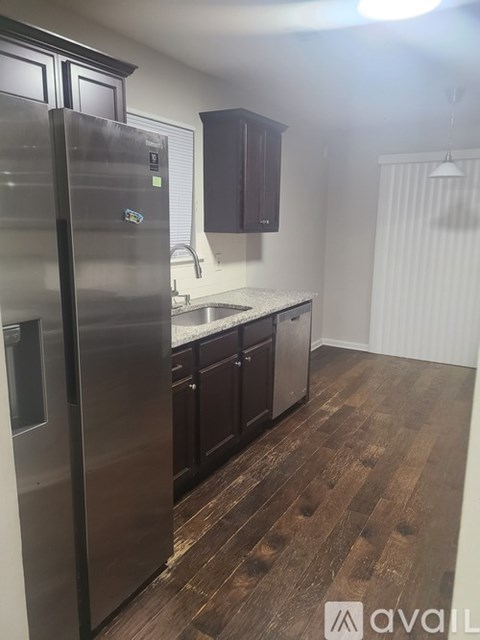 A kitchen with a stainless steel refrigerator and wooden flooring.