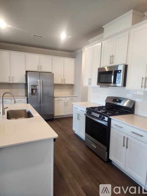 A kitchen with white cabinets and a stainless steel refrigerator.