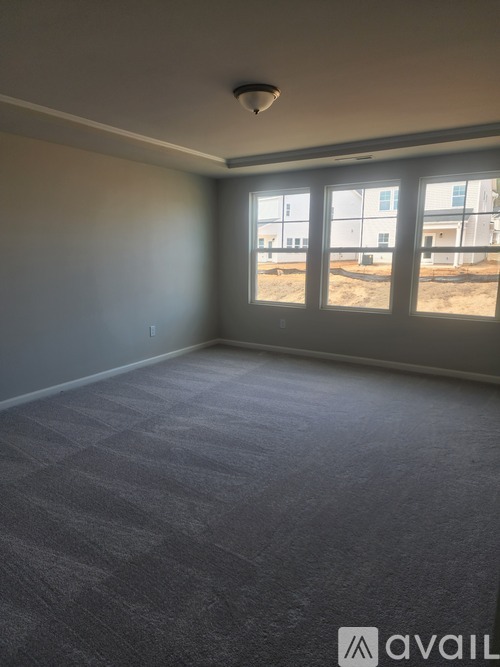 A room with carpeted floor and a window overlooking a construction site.