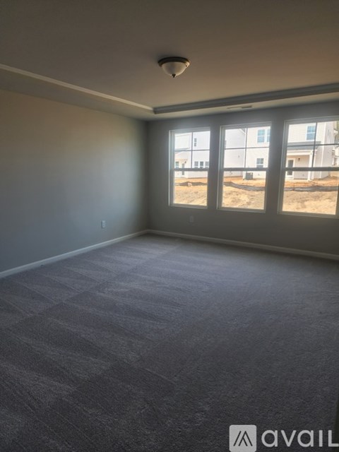 A room with carpeted floor and a window overlooking a construction site.