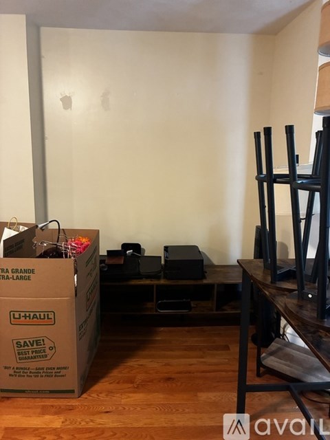 A room with a U-Haul box and a black chair.
