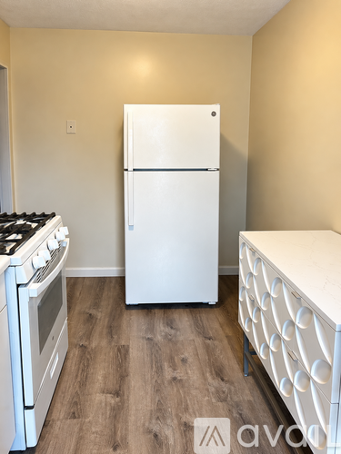 A kitchen with a white fridge, stove and a white drawer unit.