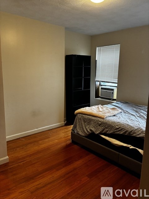 A bedroom with a bed, dresser, and window.