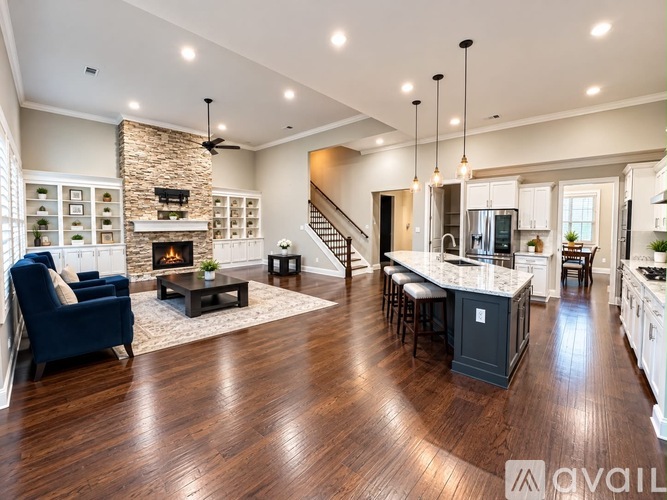 A spacious open-concept living room with a stone fireplace and hardwood floors.