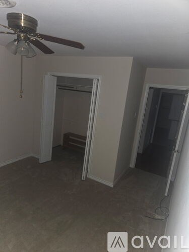 A room with a ceiling fan and a doorway leading to another room.