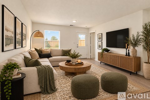 A living room with a white sofa, a wooden coffee table, and a flat-screen TV mounted on the wall.