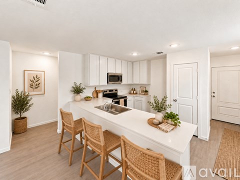 A kitchen with a white countertop and wooden chairs.