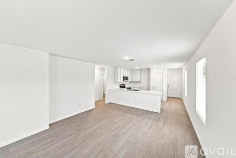 A spacious room with wooden flooring and white walls.