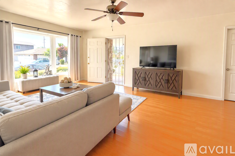 A living room with a couch, a television, and a fan.