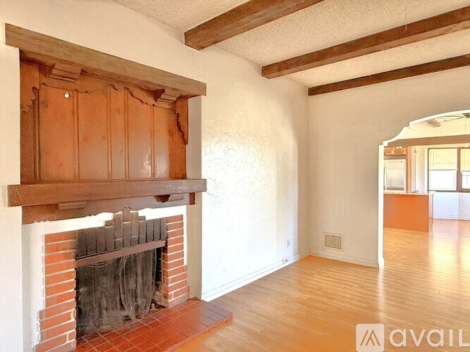 A room with a fireplace and wooden beams on the ceiling.
