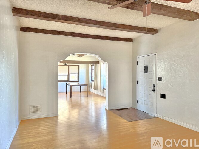 A spacious room with wooden floors and white walls.