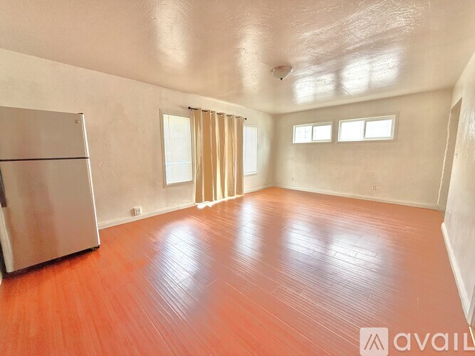 A room with wooden floors and a refrigerator.