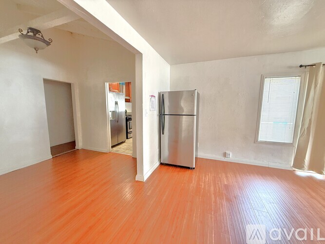 A room with a wooden floor and a refrigerator.