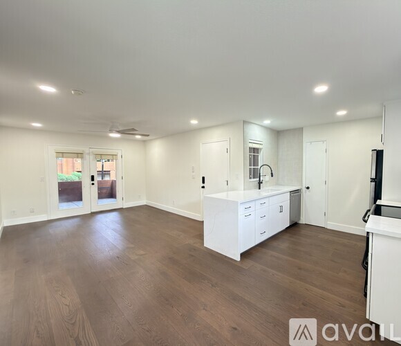 A spacious room with wooden flooring and white cabinetry.
