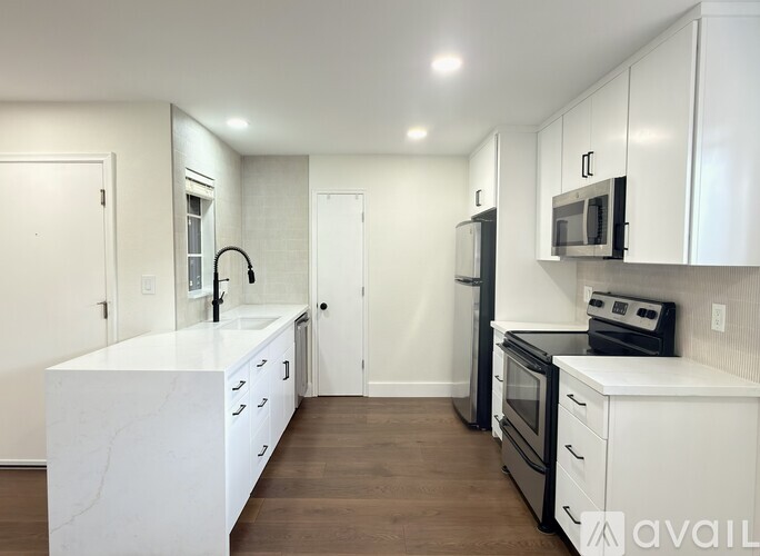 A kitchen with white cabinets and a marble island.