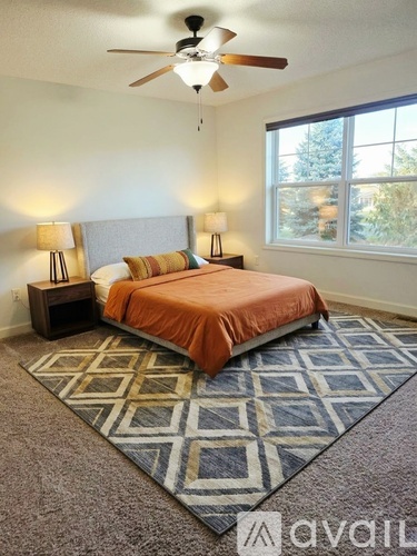 A bedroom with a bed, two lamps, and a ceiling fan.