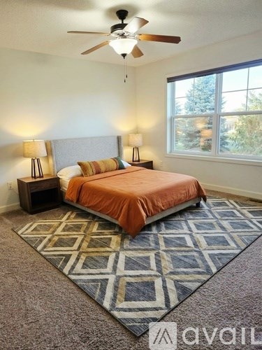 A bedroom with a bed, two lamps, and a ceiling fan.