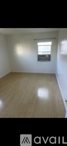 A room with wooden flooring and a window with blinds.