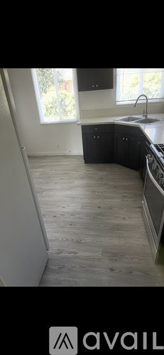 A kitchen with black cabinets and a wooden floor.
