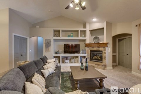 A living room with a grey couch and a fireplace.