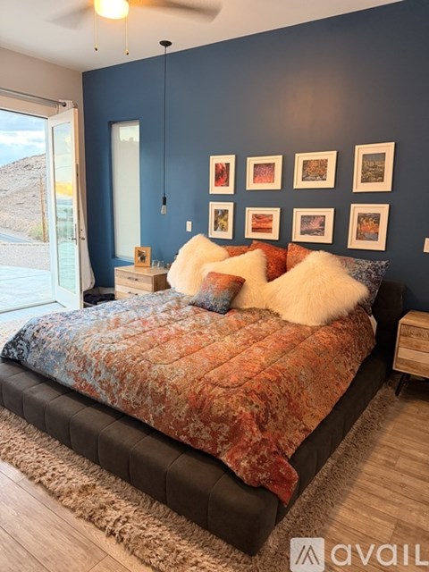 A bedroom with a bed, pillows, and pictures on the wall.