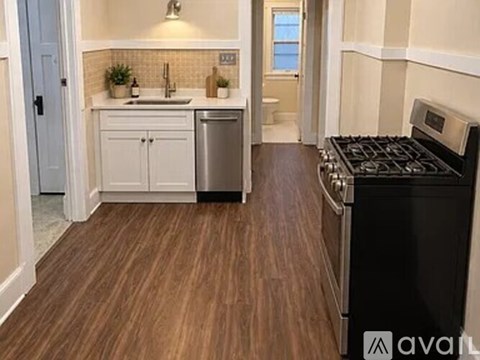 A kitchen with a black stove top oven and wooden flooring.