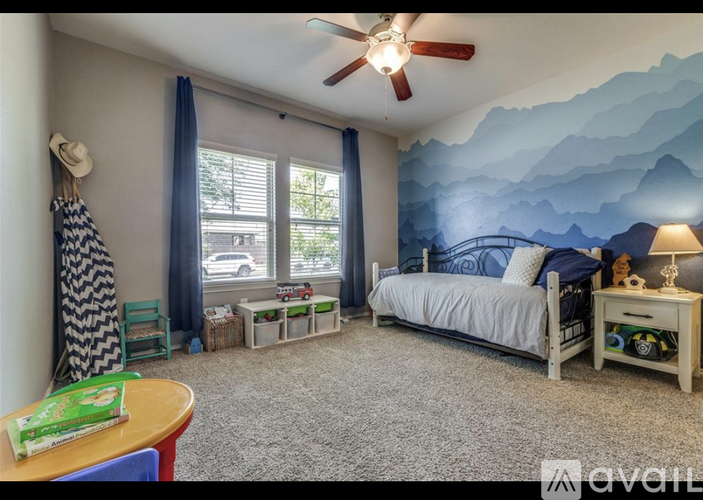 A bedroom with a mountain mural on the wall and a bed with a white comforter.