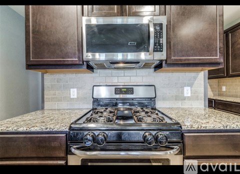 A modern kitchen with a stove top oven and microwave above it.