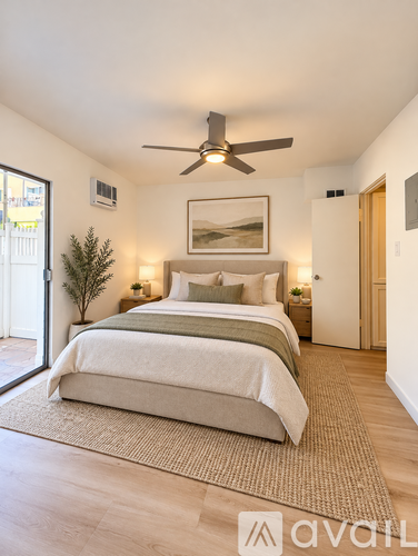 A bedroom with a bed, a ceiling fan, and a painting on the wall.