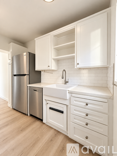 A kitchen with white cabinets and a stainless steel refrigerator.
