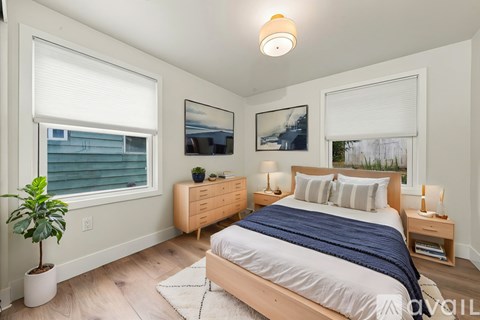 A bedroom with a bed, nightstands, and a potted plant.