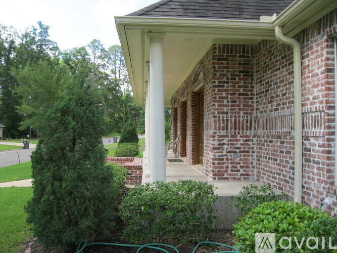 A house with a porch and a green bush in front.