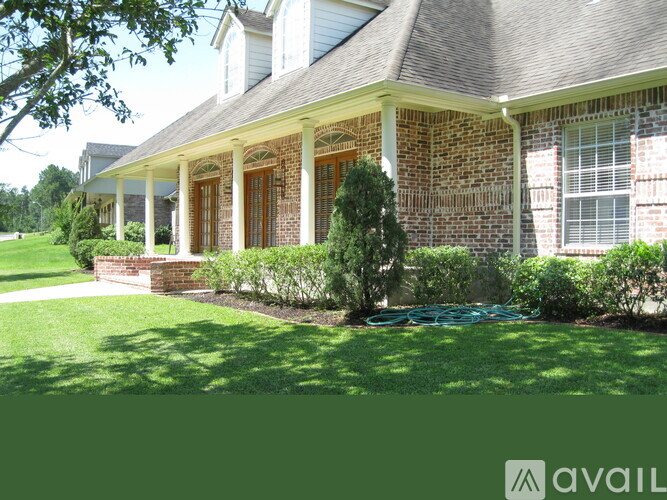 A house with a green lawn and a hose in the front yard.