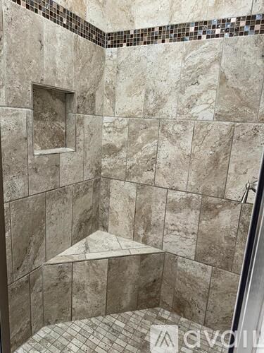 A shower with a marble tile wall and floor.